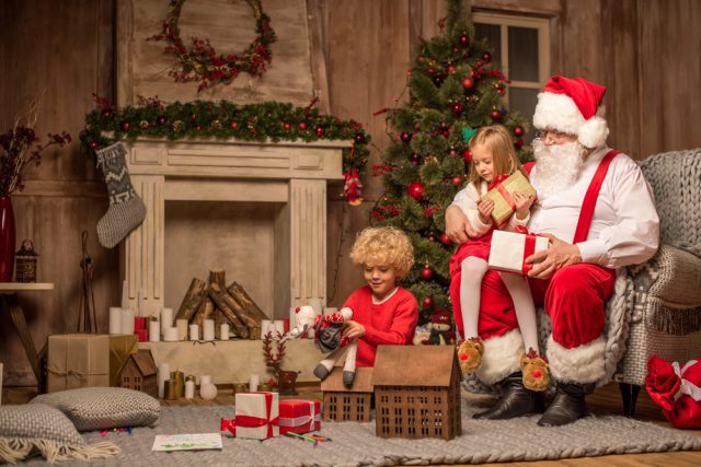 Père Noël et enfants assis près de la cheminée